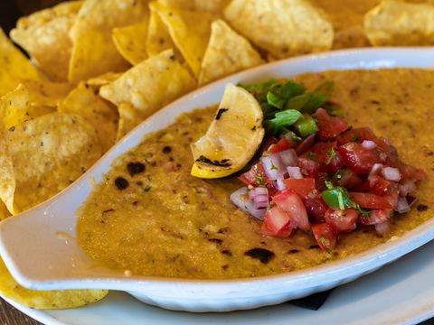 Crab and spinach dip topped with pico de gallo and a grilled lemon wedge, with corn tortilla chips
