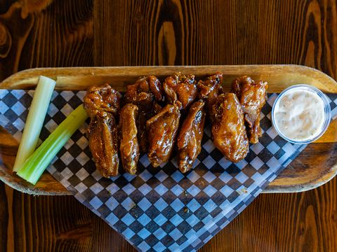 Glazed chicken wings on checkered paper with celery sticks and ranch